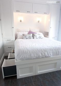 a white bed with drawers underneath it