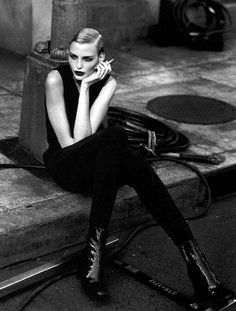 a black and white photo of a woman sitting on the curb talking on her cell phone