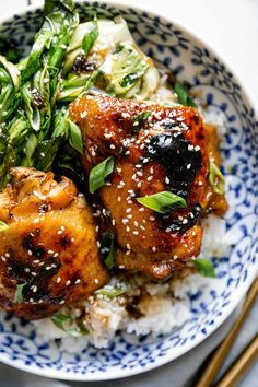 a blue and white bowl filled with rice and meat covered in teriyaki sauce