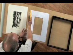 a man is holding up some pictures in front of him and placing them on the wall