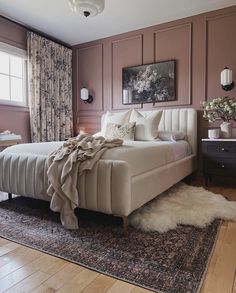 a large bed sitting on top of a hard wood floor next to a window covered in curtains