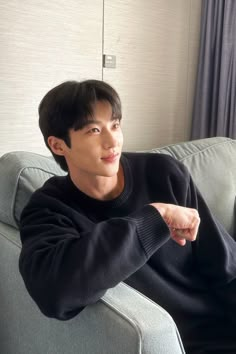 a young man sitting on top of a gray couch