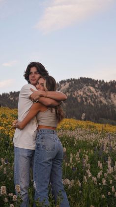 two people hugging each other in a field of flowers