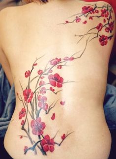 a woman's back tattoo with red flowers on her stomach and the bottom part of her body