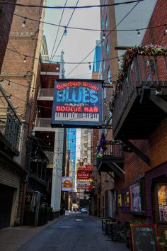 an alleyway in the city with buildings and signs hanging from it's sides