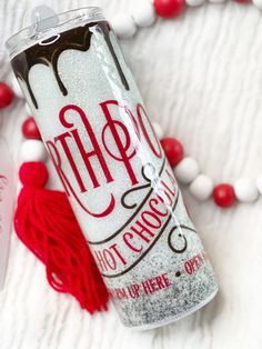 a red and white tasseled necklace next to a can of hot chocolate drink