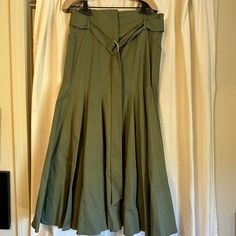 Olive Green In Color. The Skirt Features A Flared Drop Waste Silhouette With Box Plats. It Is Midi And Length And Is Finished With A Gold Tone D-Ring Buckle, And Has Hidden Front Pockets. Never Been Worn. Italian Size 46 Which Is About A Us Size 10. Fitted Belted Flared Skirt Bottoms, Fitted Belted Flared Skirt, Relaxed Fit Belted Flared Skirt, Belted Full Skirt For Work, Green A-line Bottoms For Workwear, Fitted Long Skirt With Belt, Belted Long Relaxed Skirt, Elegant Belted Full Skirt Bottoms, Elegant Belted Full Skirt