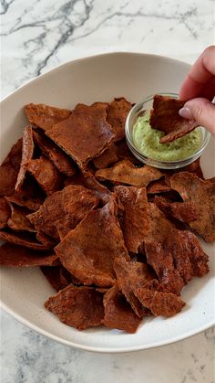 a white plate topped with tortilla chips and guacamole dipping sauce