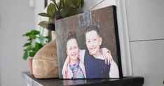 a couple of pictures sitting on top of a shelf next to a potted plant