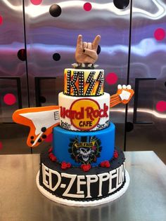 a three tiered cake decorated with rock and roll logos