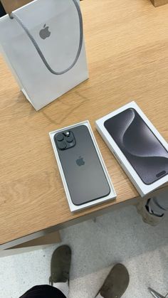 an apple phone is sitting on the table next to its box and bag, which are also in front of it