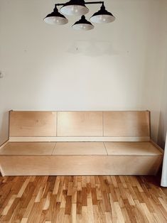 a wooden bench sitting on top of a hard wood floor next to two light fixtures