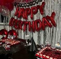 a birthday party with red balloons and black table cloths, silver streamers and decorations