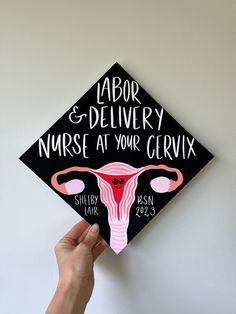 a hand holding up a black and pink graduation cap