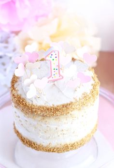 a birthday cake with white frosting and gold sprinkles on a plate