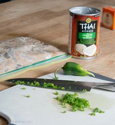 a can of jalapeno sitting on top of a cutting board next to a knife