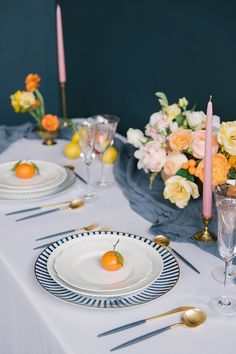 the table is set with plates, silverware and flowers in vases on it