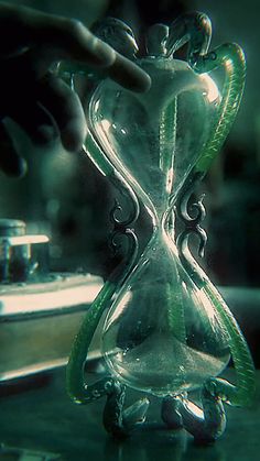 an hourglass sitting on top of a table next to a person's hand