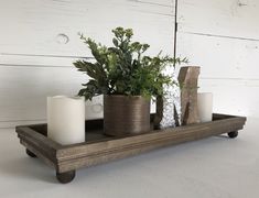 a wooden tray with candles and plants on it