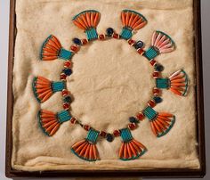 an orange and blue beaded necklace in a wooden box