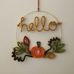 an ornament hanging from a wall with the word hello written in gold thread