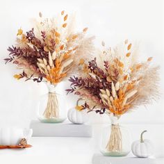 two vases filled with dried flowers and pumpkins