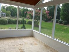 an empty sun room with large windows and tiled floor