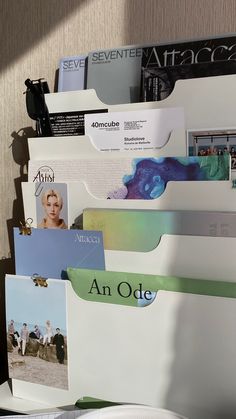 several folders stacked on top of each other in front of a wall mounted magazine rack