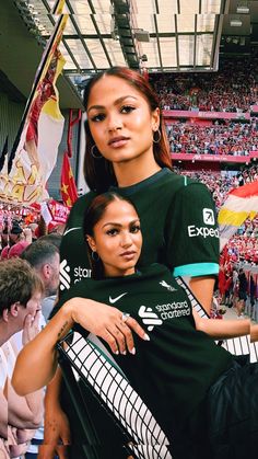 two women are holding each other in front of a crowd at a sporting event with flags on the stands