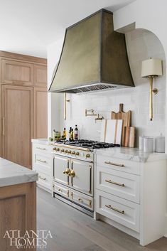 a stove top oven sitting inside of a kitchen next to white counter tops and wooden cabinets