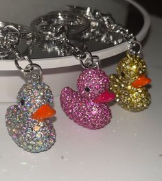 three glittered ducks sitting next to each other on a white surface with silver rings