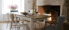 a dining room table with chairs around it and a fire place in the fireplace behind it