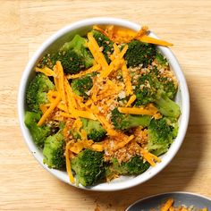 a white bowl filled with broccoli and cheese on top of a wooden table