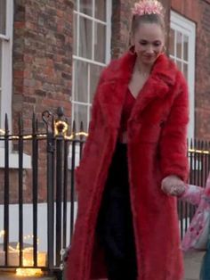 a woman in a red coat is walking down the street