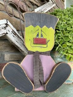 a wooden cut out of a cartoon character sitting next to a potted green plant