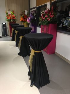 tables with black tablecloths and gold sashes are lined up against the wall