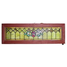 an old stained glass window with flowers on it's side, hanging from a wooden frame