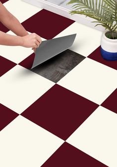 a person cutting up a piece of paper on top of a checkerboard floor