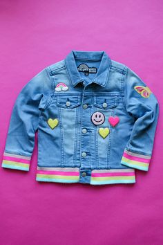 Rainbow on rainbow on rainbow? Yes, please! Our Custom Rib Denim Jacket is so soft and so fun. It's easy to see why this is a favorite. We paired our Rainbow Striped letters with our stacked Supersize Heart. We accented with glitter chenille hearts, smileys, a butterfly on the sleeve...and one more glitter rainbow for good measure. This jacket comes with all the patches you see here. Just add your name! Easy Peasy!Bonus! It's boutique quality, eco-friendly, and arrives in awesome packaging (made Fun Pink Spring Outerwear, Fun Long Sleeve Outerwear For Playtime, Playful Outerwear For Spring Playtime, Spring Playwear Cotton Outerwear, Cute Medium Wash Cotton Denim Jacket, Spring Cotton Outerwear For Play, Cute Multicolor Outerwear For Playtime, Fun Multicolor Cotton Outerwear, Cute Cotton Denim Jacket