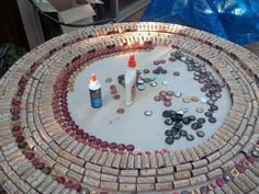 a table made out of bottle caps and bottles on top of a circular surface with one bottle in the middle