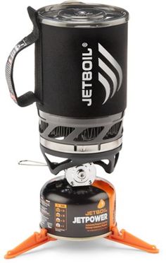 the jetboil stove is sitting on top of an orange and black stand with its lid open