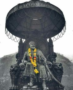 the statue is sitting in front of an outdoor structure with yellow garlands on it