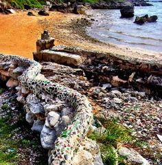 there is a rock wall on the beach next to the water and rocks that have been placed together