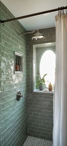 a bathroom with green tiles and a white shower curtain