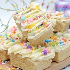 several pieces of cake with white frosting and sprinkles on a cutting board