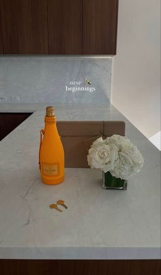 a bottle of champagne sitting on top of a counter next to a vase filled with white flowers