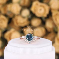 a blue diamond ring sitting on top of a white box with roses in the background