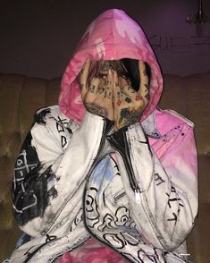 a person covered in graffiti sitting on a couch with their hands covering their face and mouth