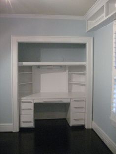 an empty white desk with drawers and shelves