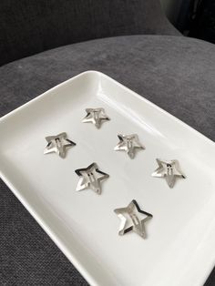 five silver stars on a white plate sitting on a gray couch in the living room